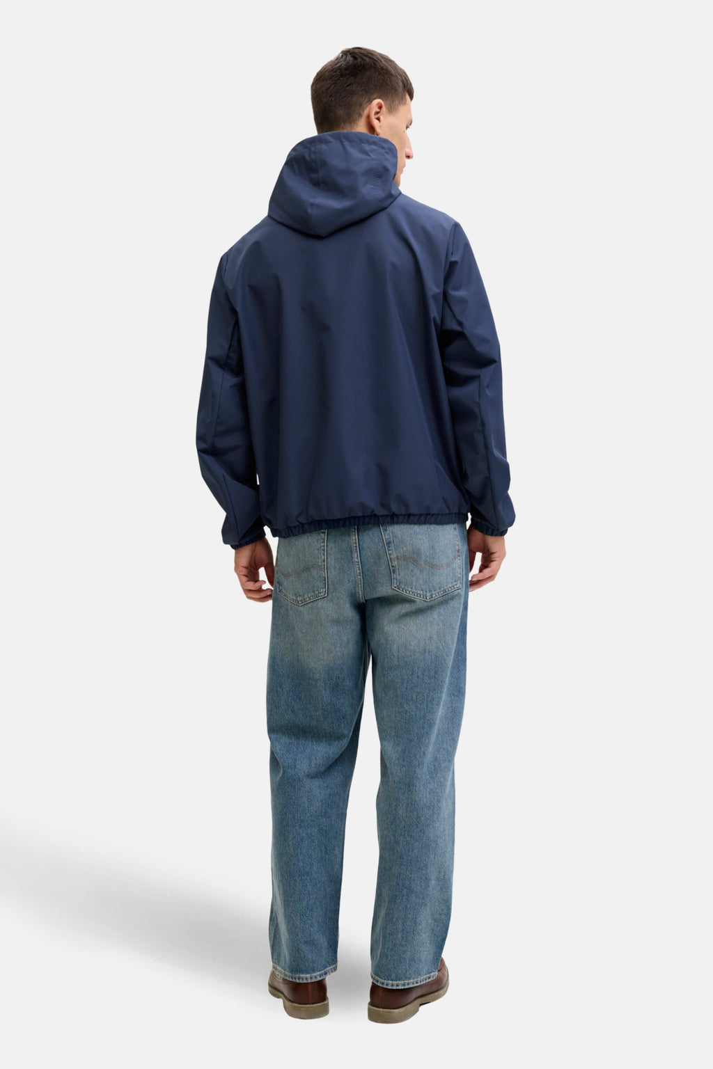 Korte blauwe jas van ORIGINALS BY JACK & JONES, met capuchon en gecombineerd met wijde jeans en bruine schoenen.
