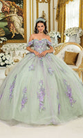 A woman in the Quinceanera Dress 5023 by Dancing Queen, featuring a light green corset bodice and purple 3D flowers, wears a tiara and stands in an ornate room with gold accents and white floral arrangements.