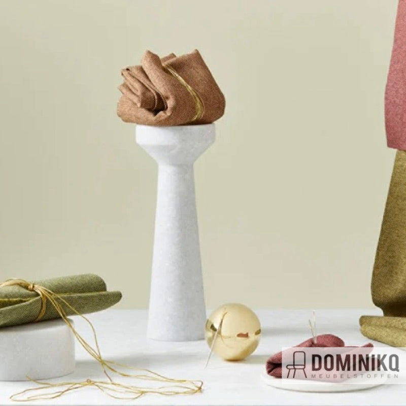 Verzameling van Camira Fabrics stoffen in neutrale tinten op een marmeren sokkel, met gouden accenten en moderne styling.