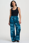 Woman wearing blue patterned pants and a black top on a white background