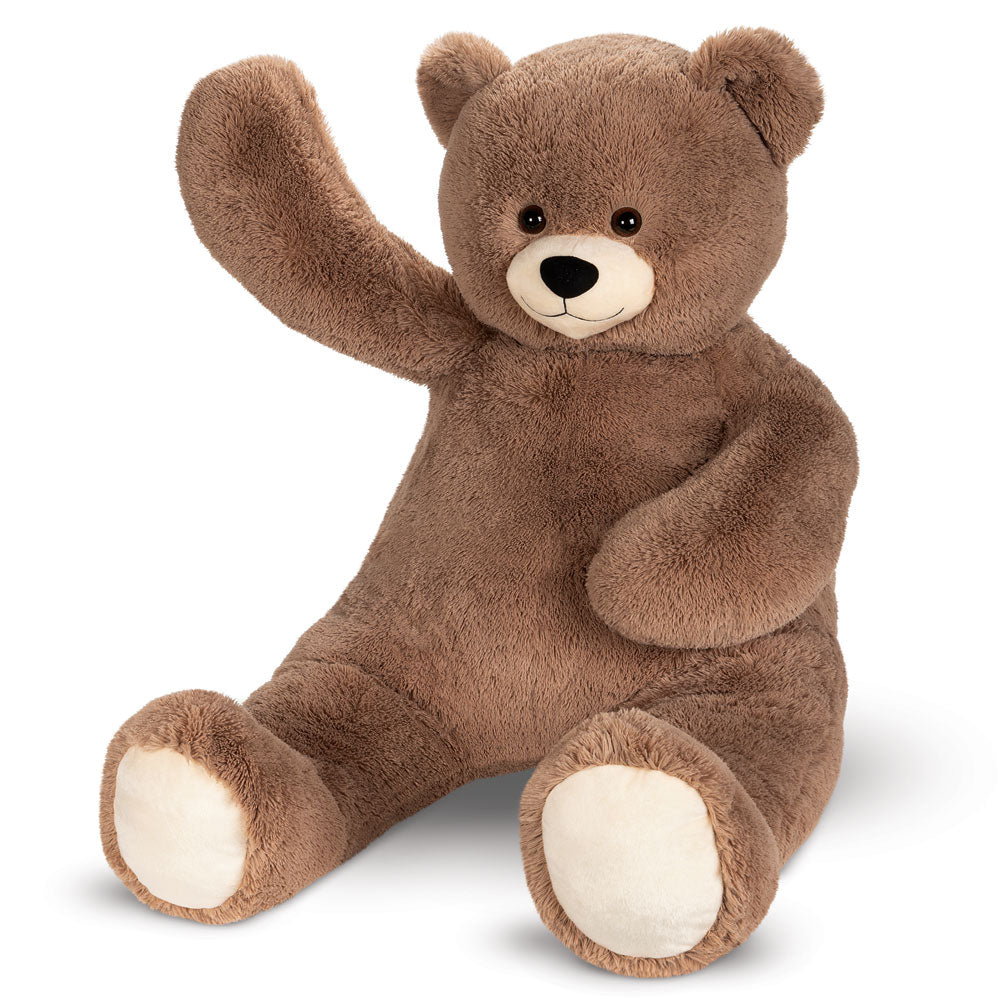 Large brown teddy bear with soft fur and beige paw pads sitting with one paw raised.